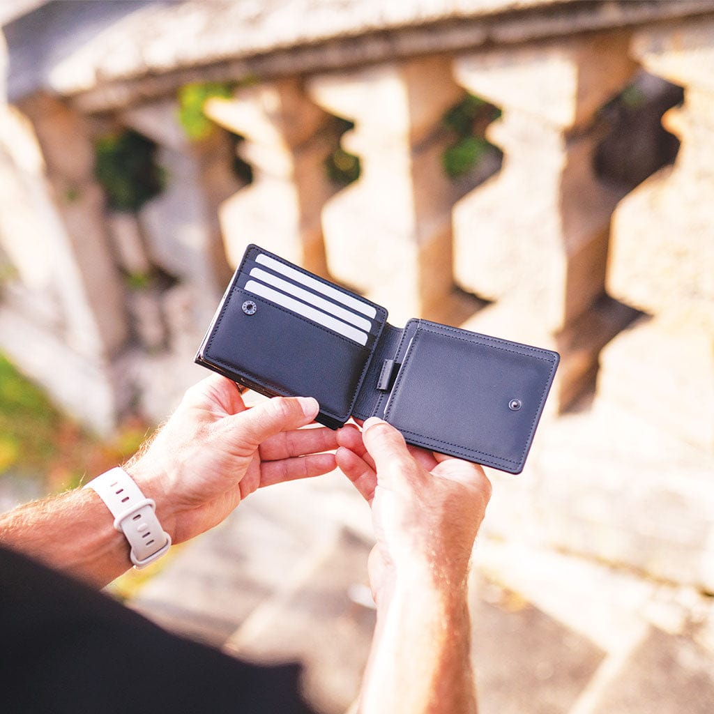 black flap boy xl magic wallet held by hands with a blurred architectural background