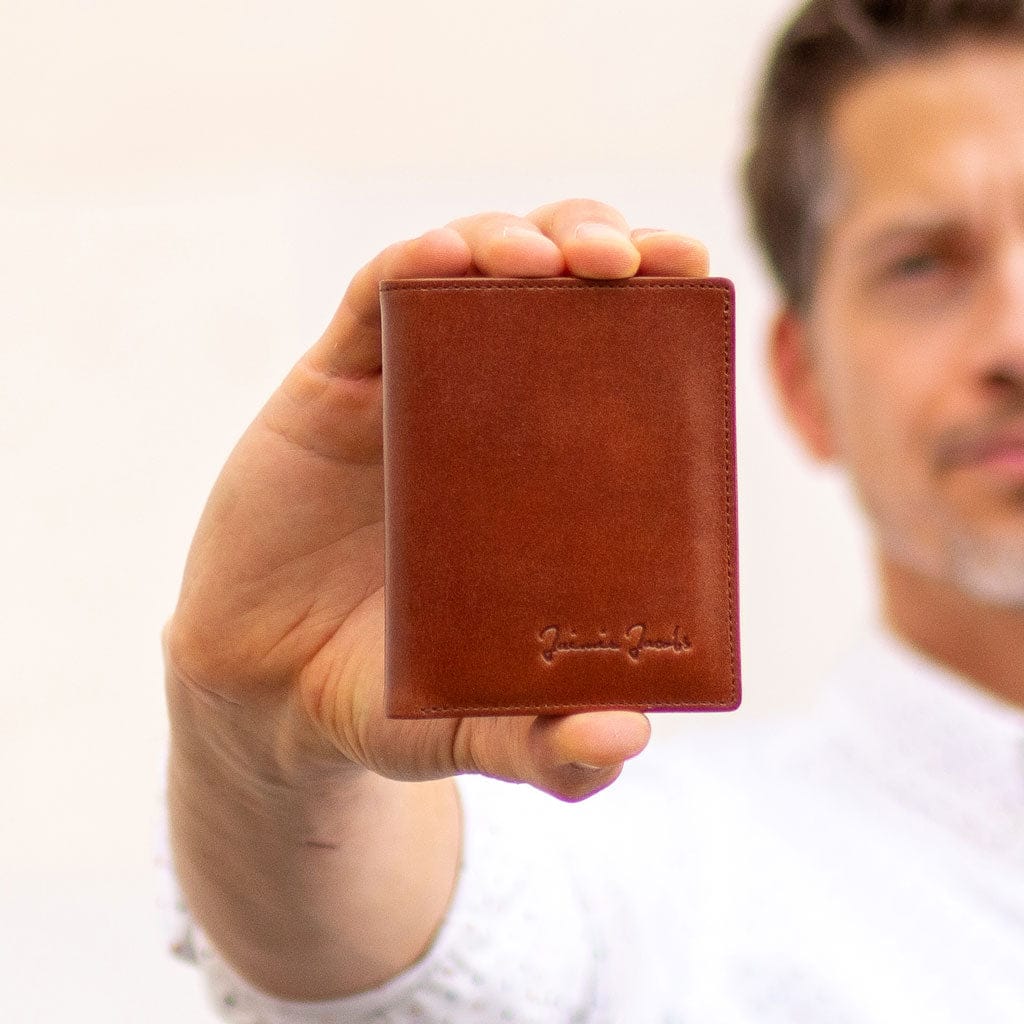 Man holding a brown slimstar leather wallet with a blurred background